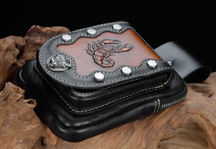 Black leather wallet with studded design and embossed dragon on a wooden surface
