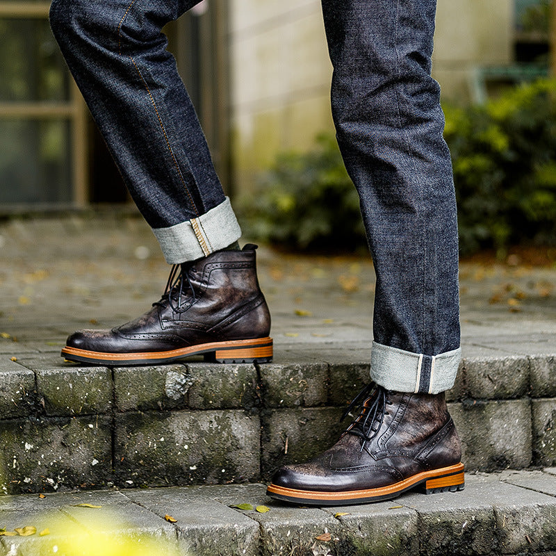 Person wearing dark leather boots and blue jeans standing on stone steps.