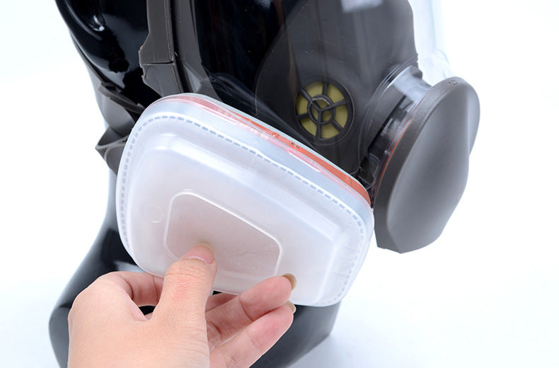 Hand holding a filter for a respirator mask on a white background