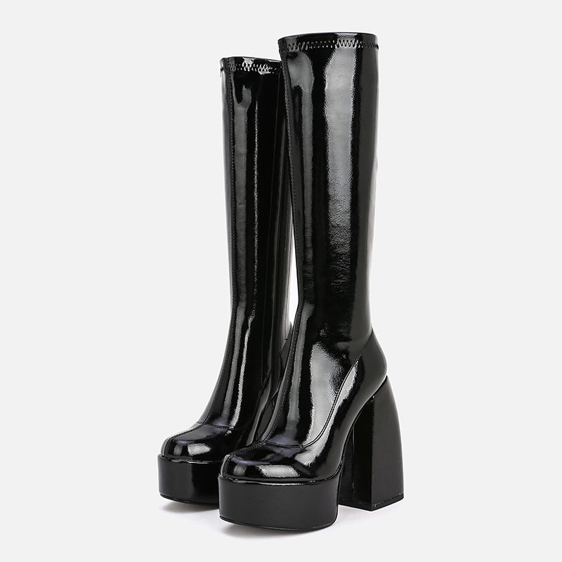 Black patent leather knee-high boots on a white background