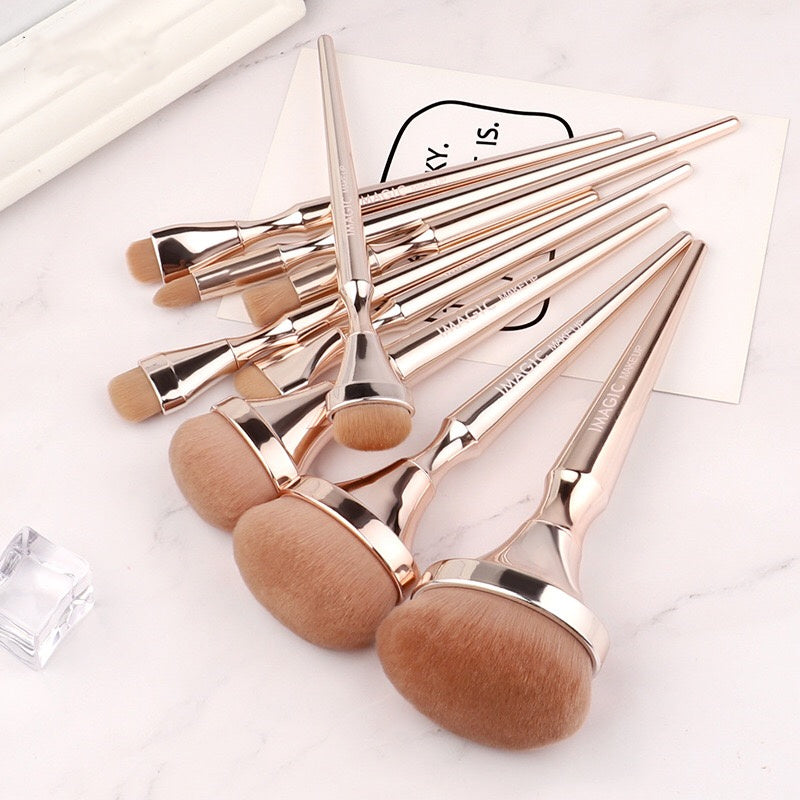 Set of rose gold makeup brushes on a white background