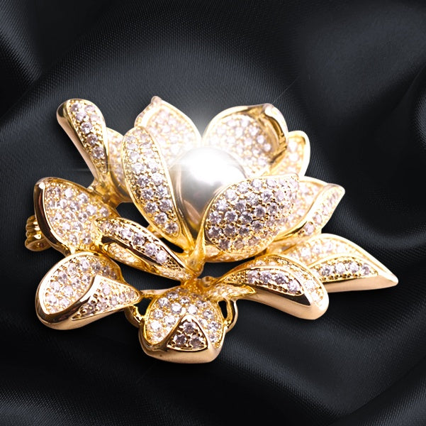 Gold lotus flower brooch with pearl center on a black background