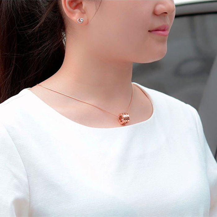 Close-up of a person wearing a rose gold necklace and earrings.