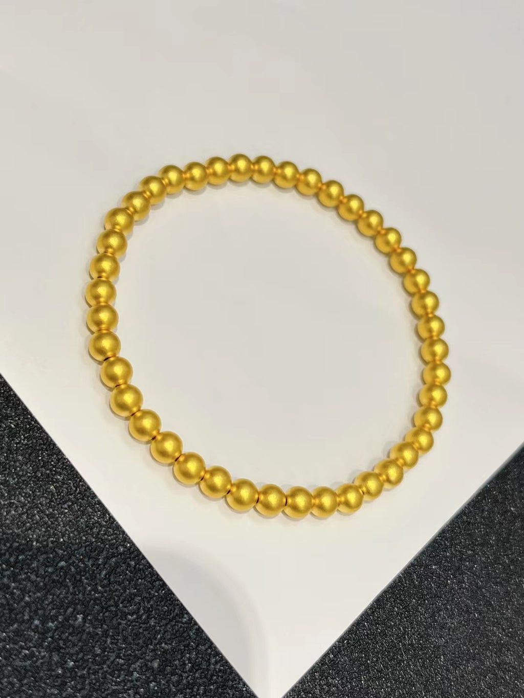 Gold beaded necklace on a white and black textured background