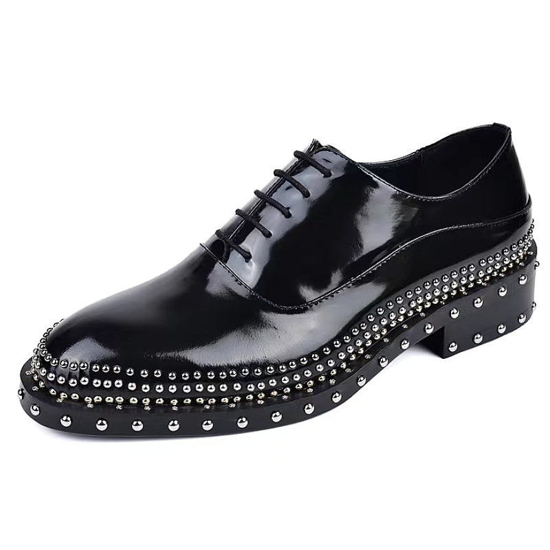 Black patent leather shoe with studded details on a white background