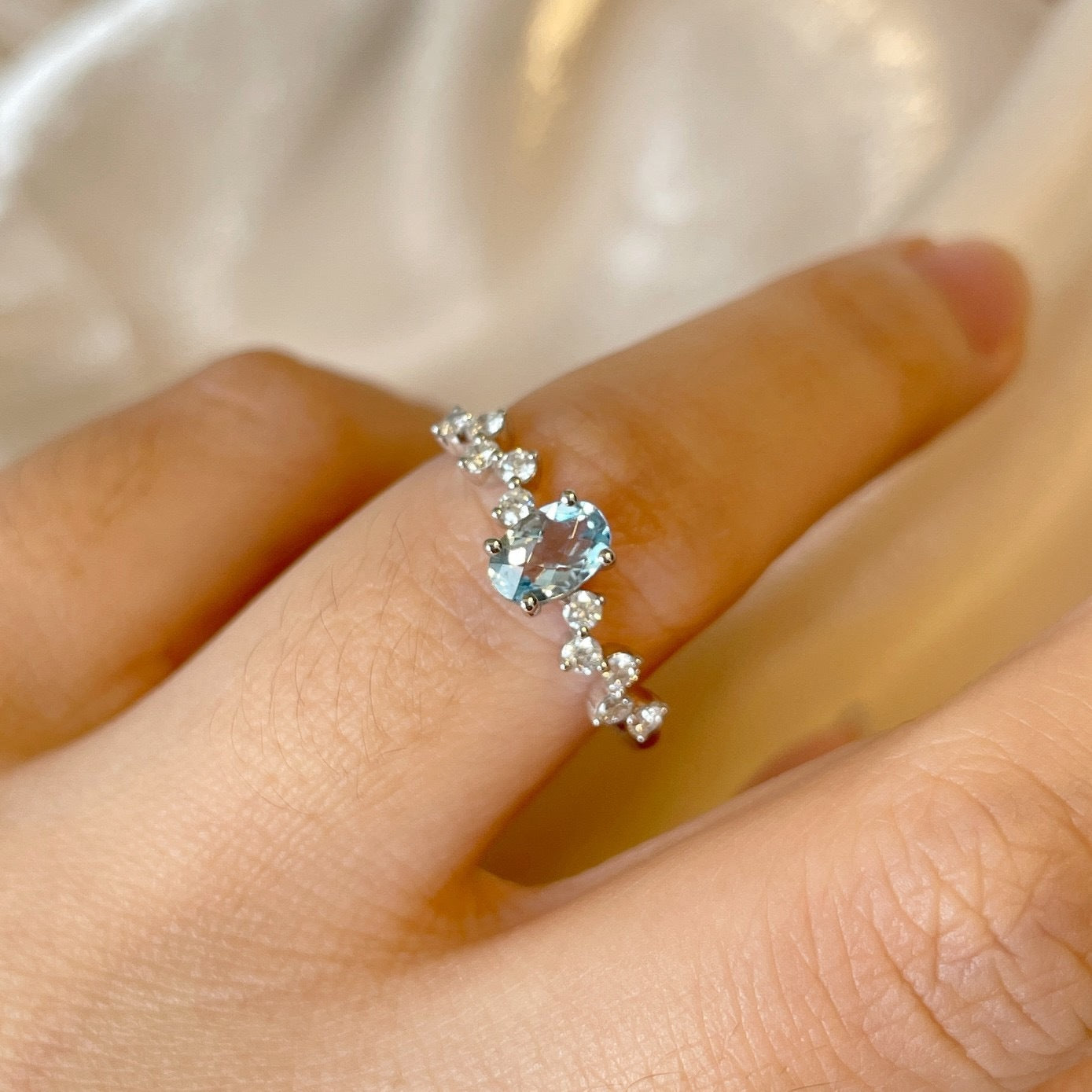 Silver ring with a blue gemstone on a hand against a soft background