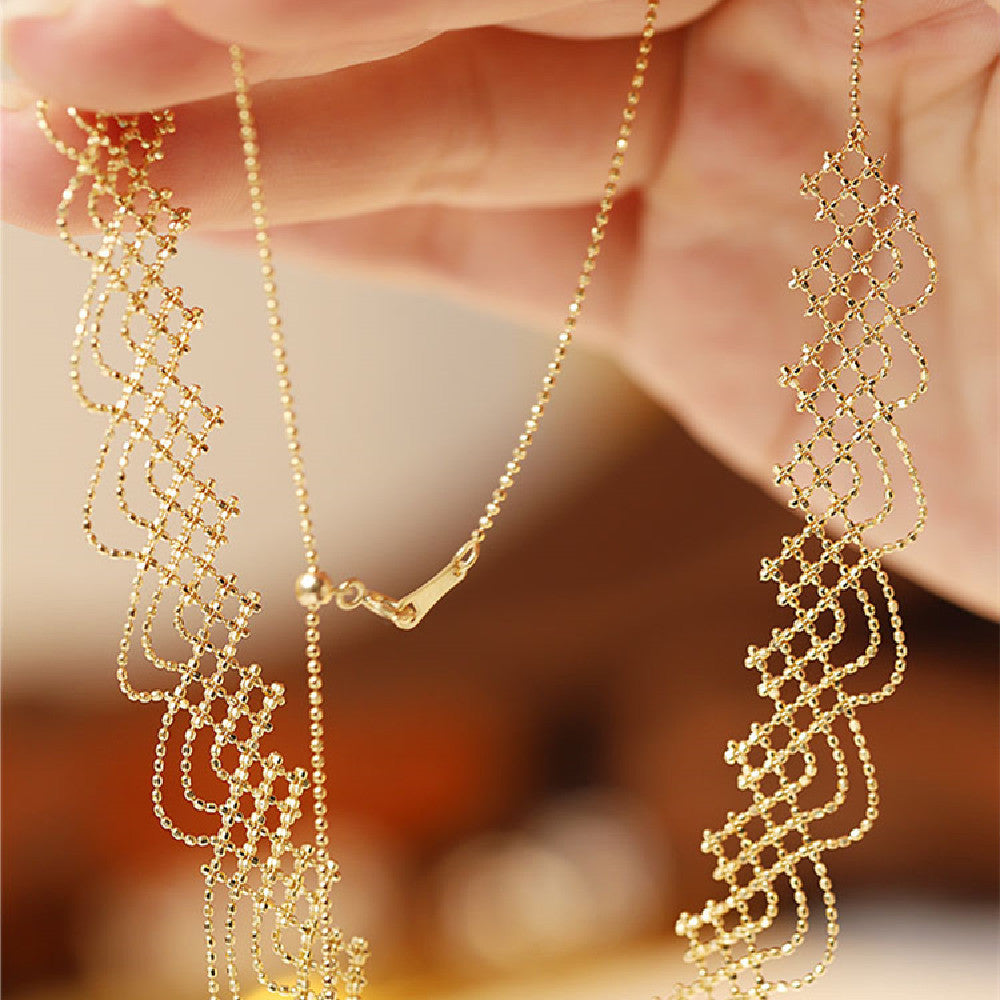 Gold necklace and earrings held by a hand against a blurred background