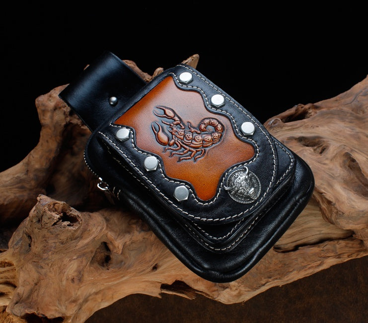 Black leather wallet with scorpion design on a wooden surface