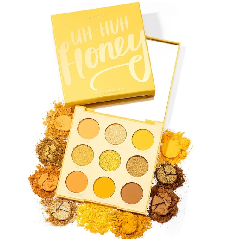 Makeup palette with 'Uh-Huh Honey' text on a yellow box, surrounded by eyeshadow shades.
