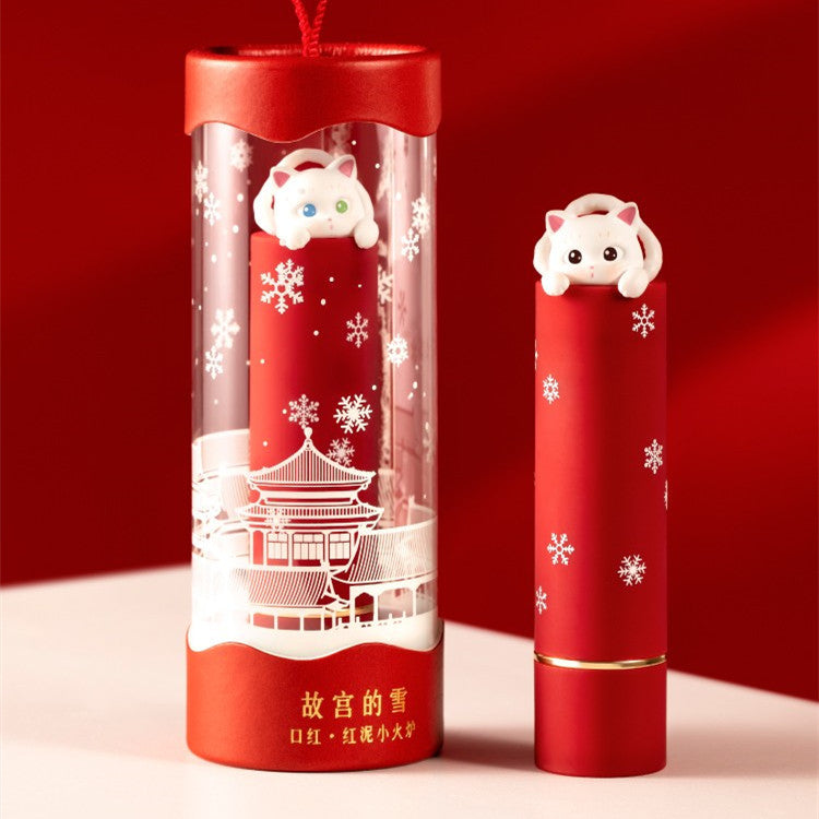 Red lipstick with cat-shaped cap and transparent tube on a red background