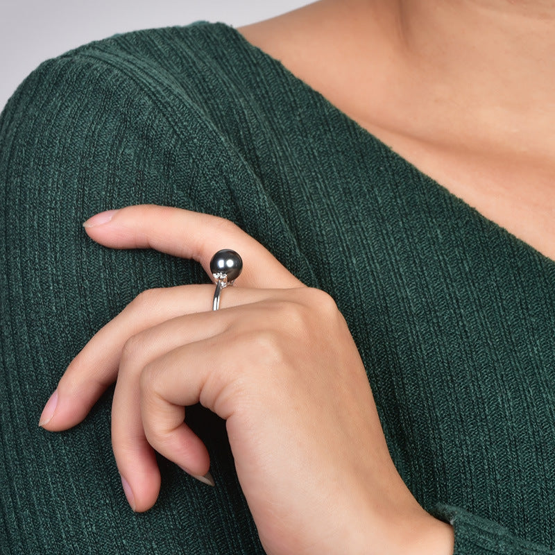 Close-up of a hand wearing a silver ring on a green textured fabric background