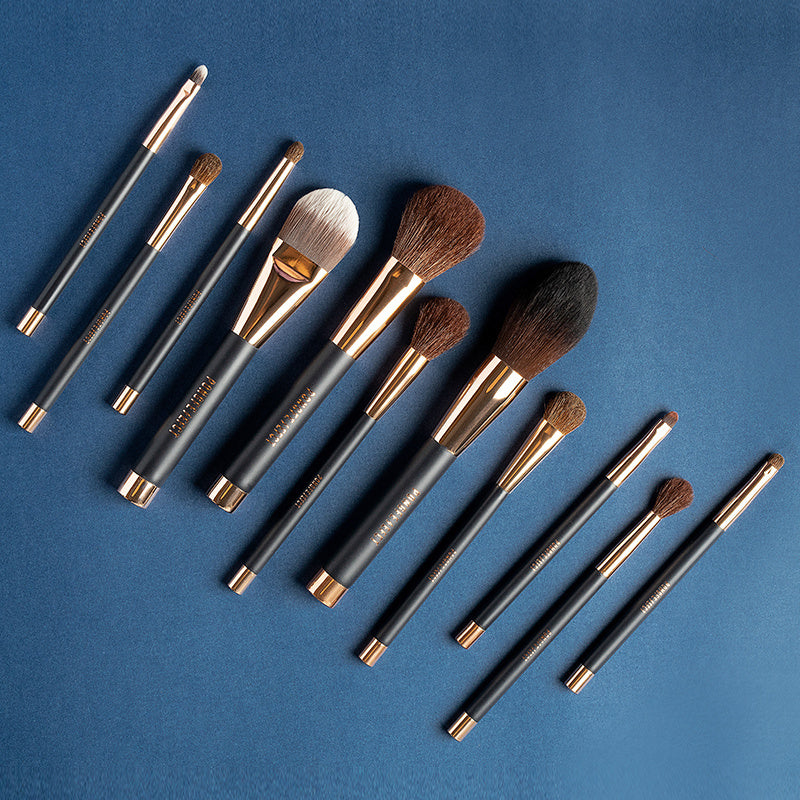 Set of makeup brushes with black and gold handles on a blue background