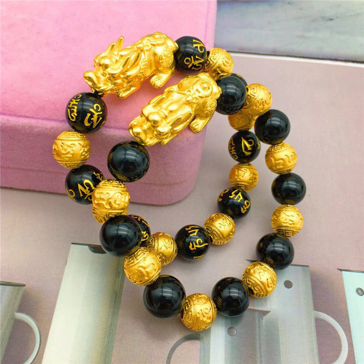 Bracelet with gold and black beads on a pink surface