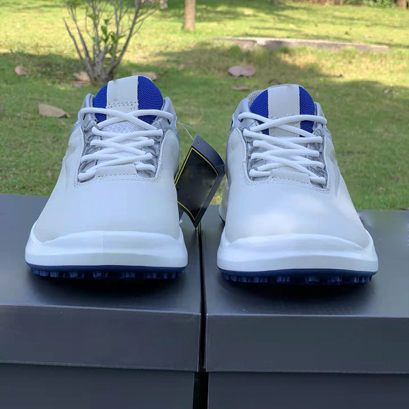 White golf shoes with blue accents on a black surface outdoors.