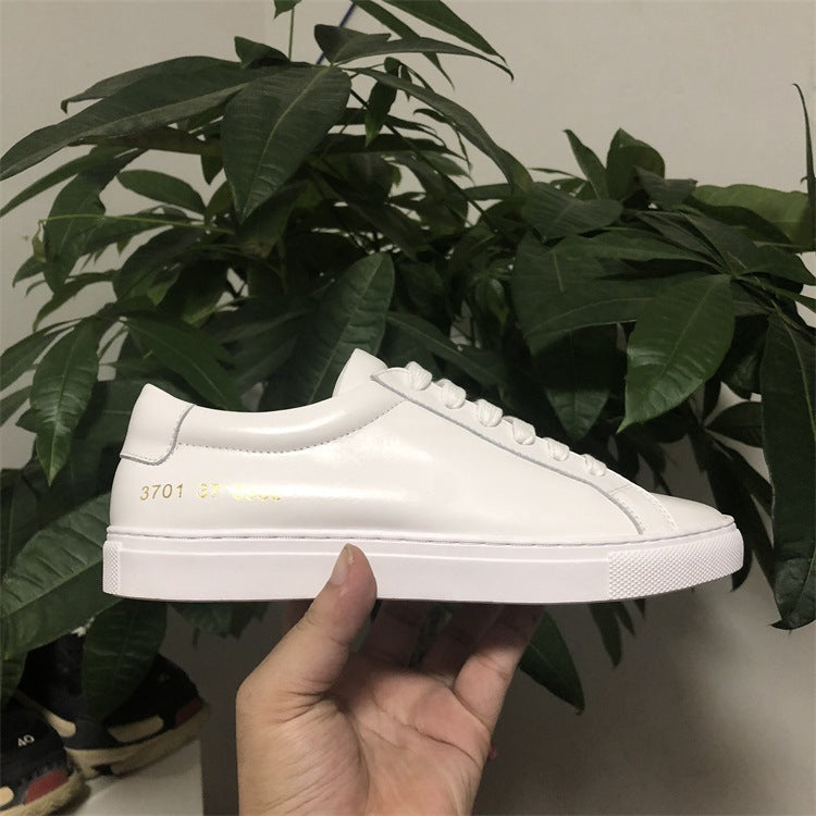 White sneaker held in front of a plant