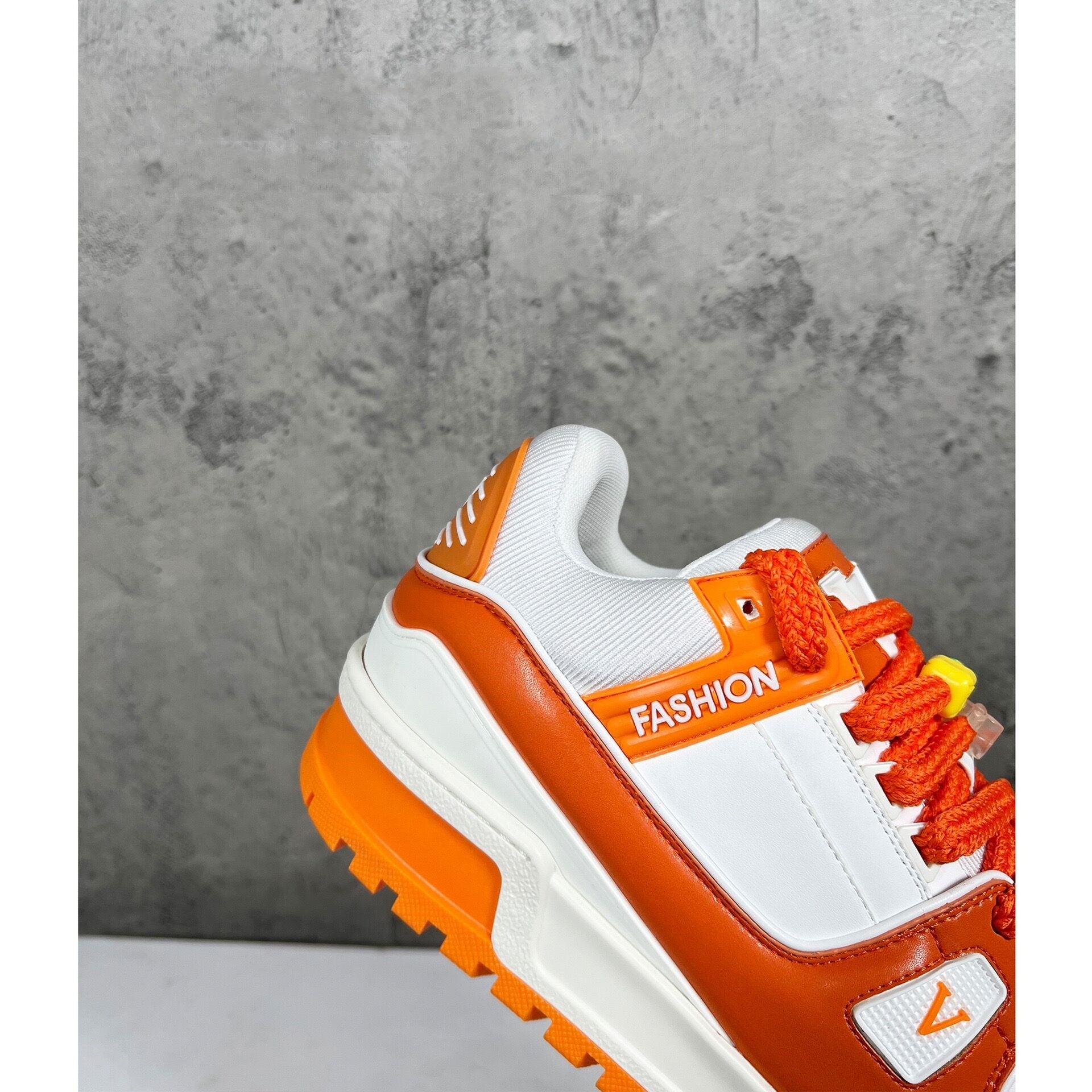 Orange and white sneaker with 'FASHION' text on a gray background