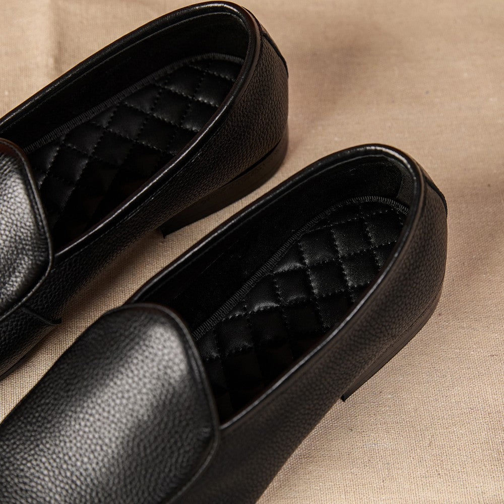 Pair of black loafers on a beige fabric background