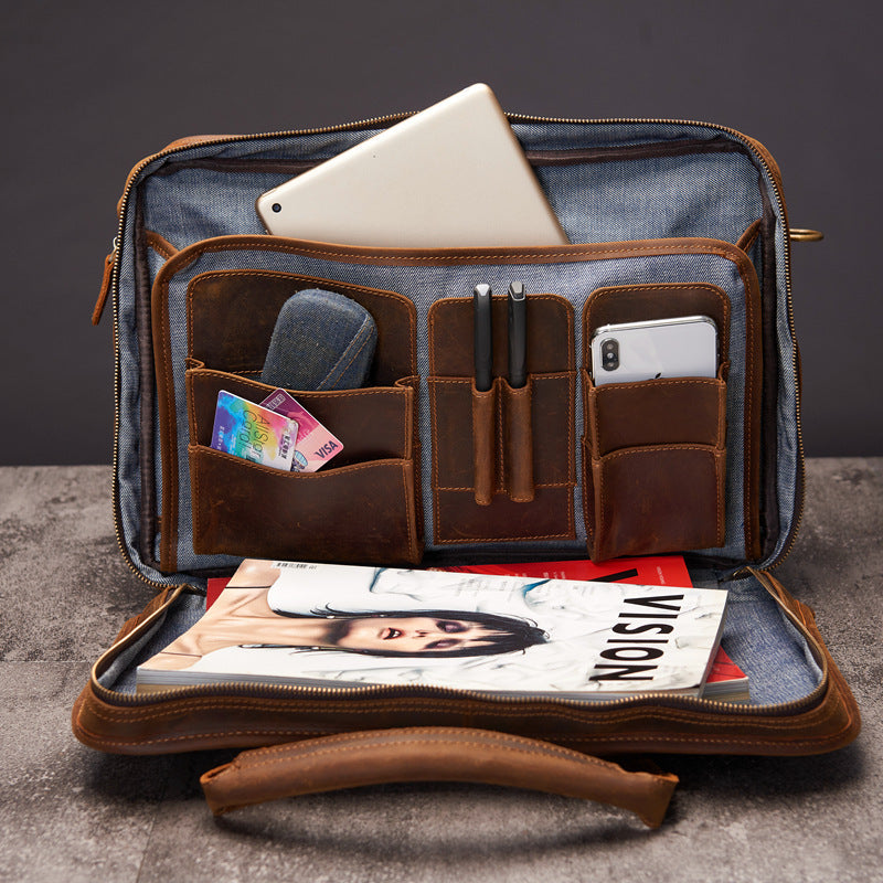 Open leather briefcase with compartments and items on a dark background