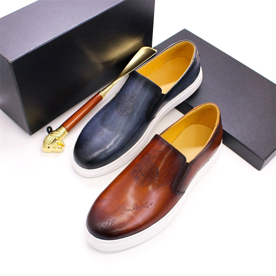 Pair of brown and black loafers with a gold shoe horn on a white background