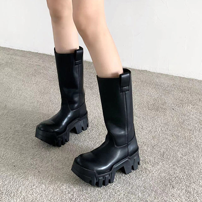 Black platform boots worn by a person on a gray carpet