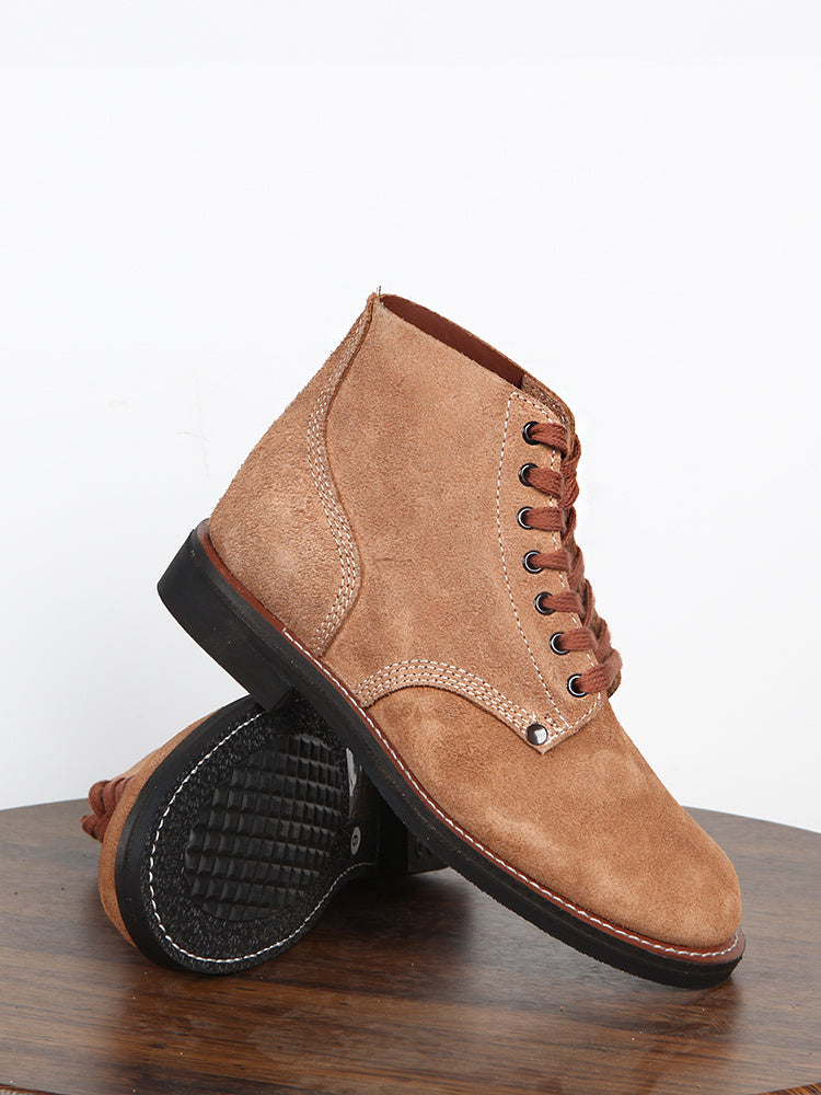 Brown suede boot with black sole on a wooden surface