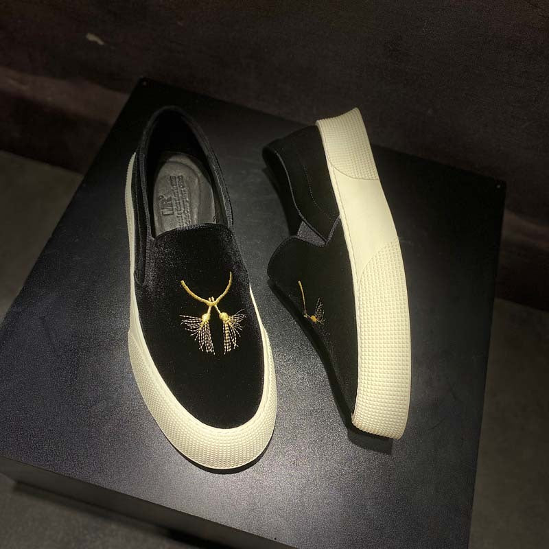 Black loafers with gold embellishments on a dark surface