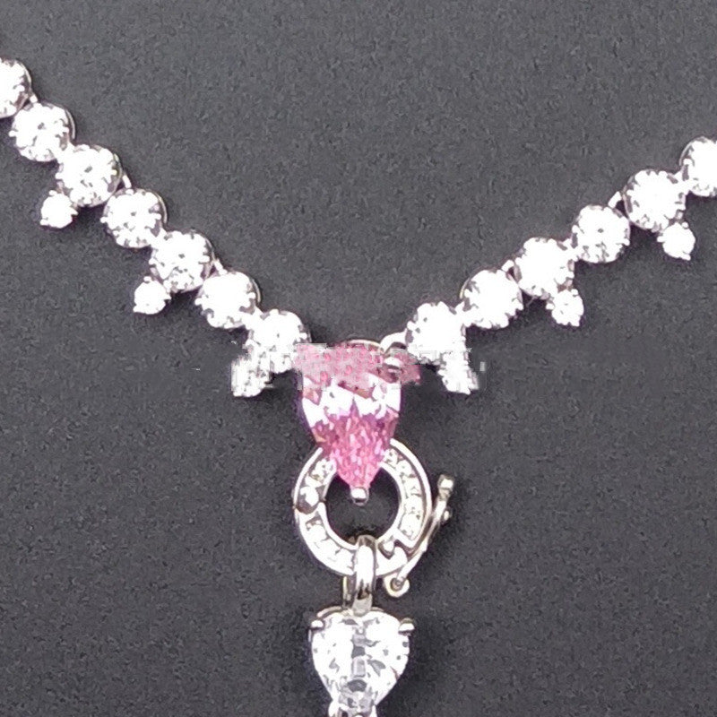 Necklace with pink gemstone and heart charm on a dark background