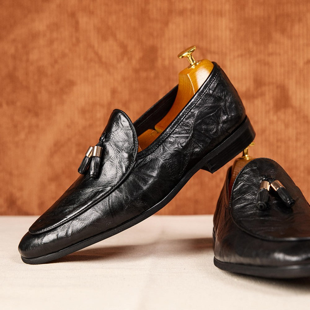 Black leather loafers with tassels on a wooden background