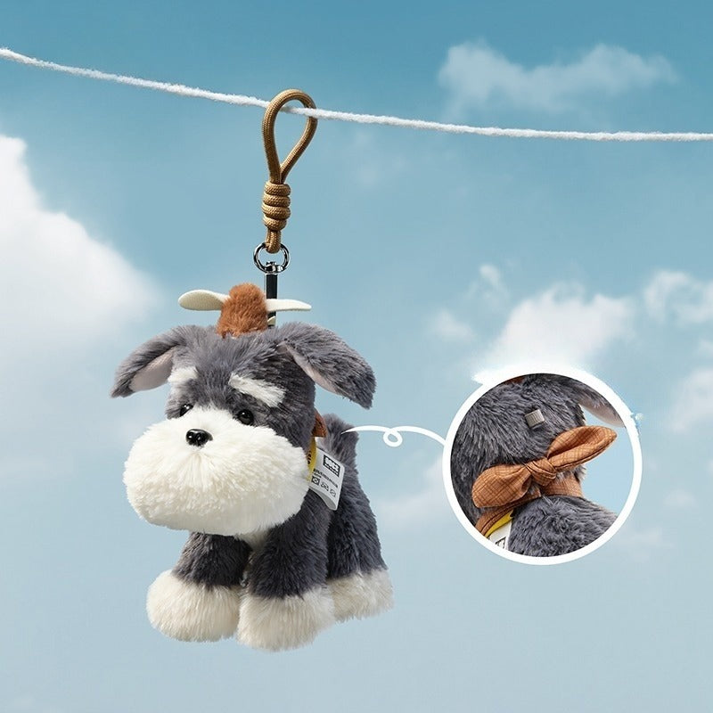 Plush dog toy with a scarf hanging on a line against a blue sky.