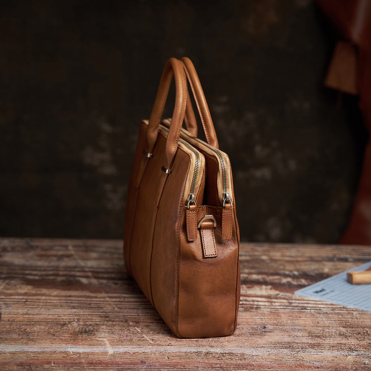 Brown leather handbag on a wooden surface with a dark background