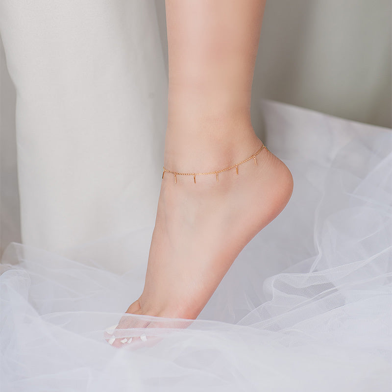 Gold anklet on a foot with a soft background