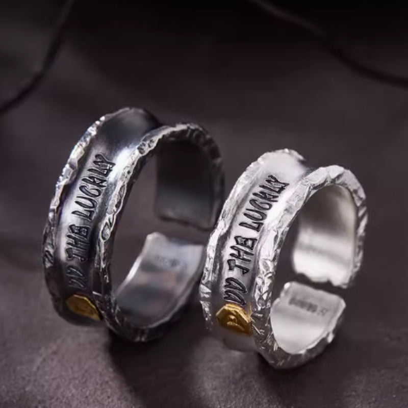 Two silver rings with engraved text on a dark surface