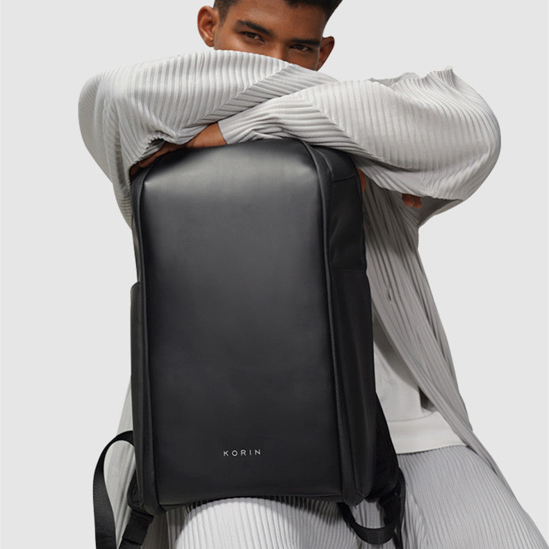 Person wearing a black backpack with 'KORIN' branding on a light gray background