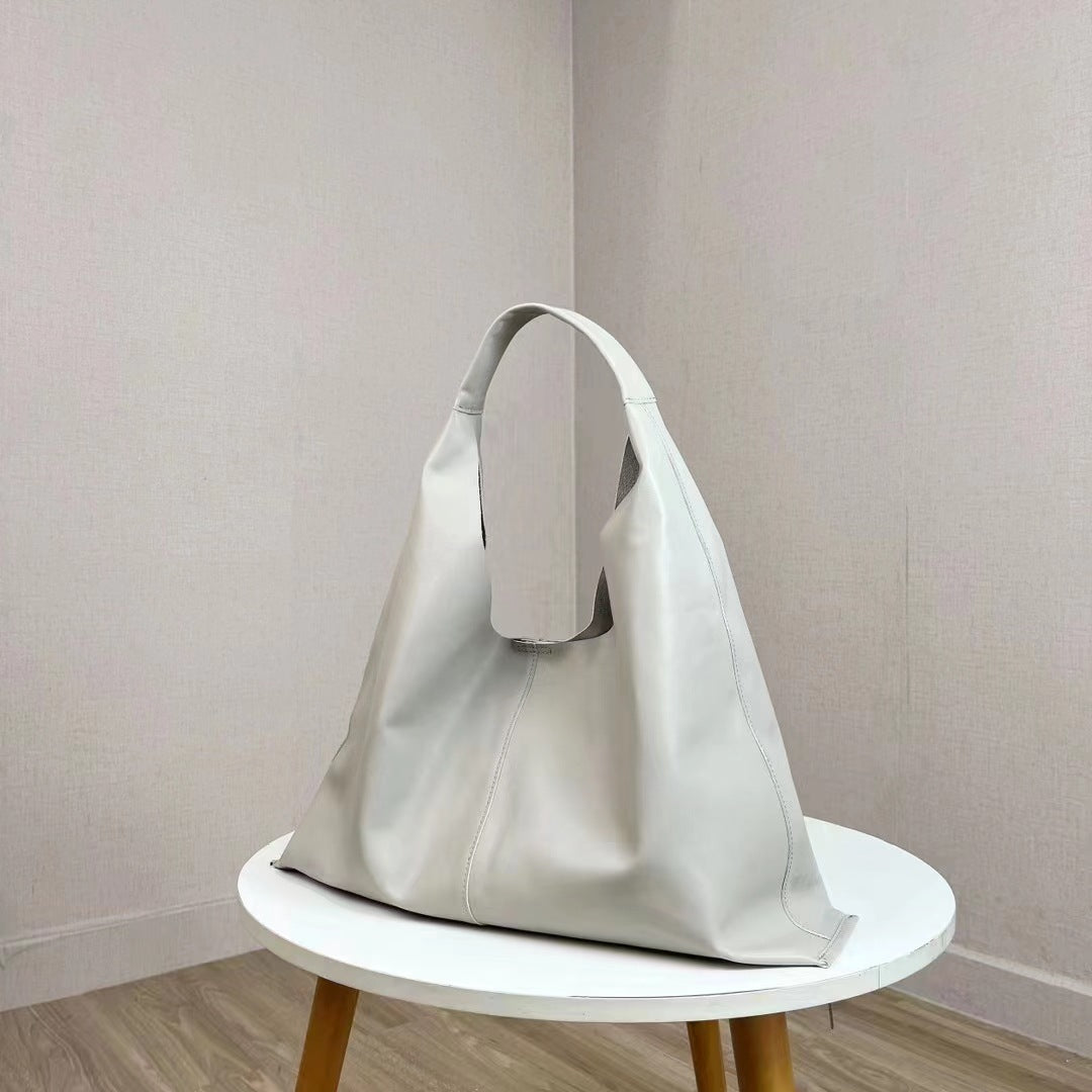 Light gray handbag on a white table against a plain wall