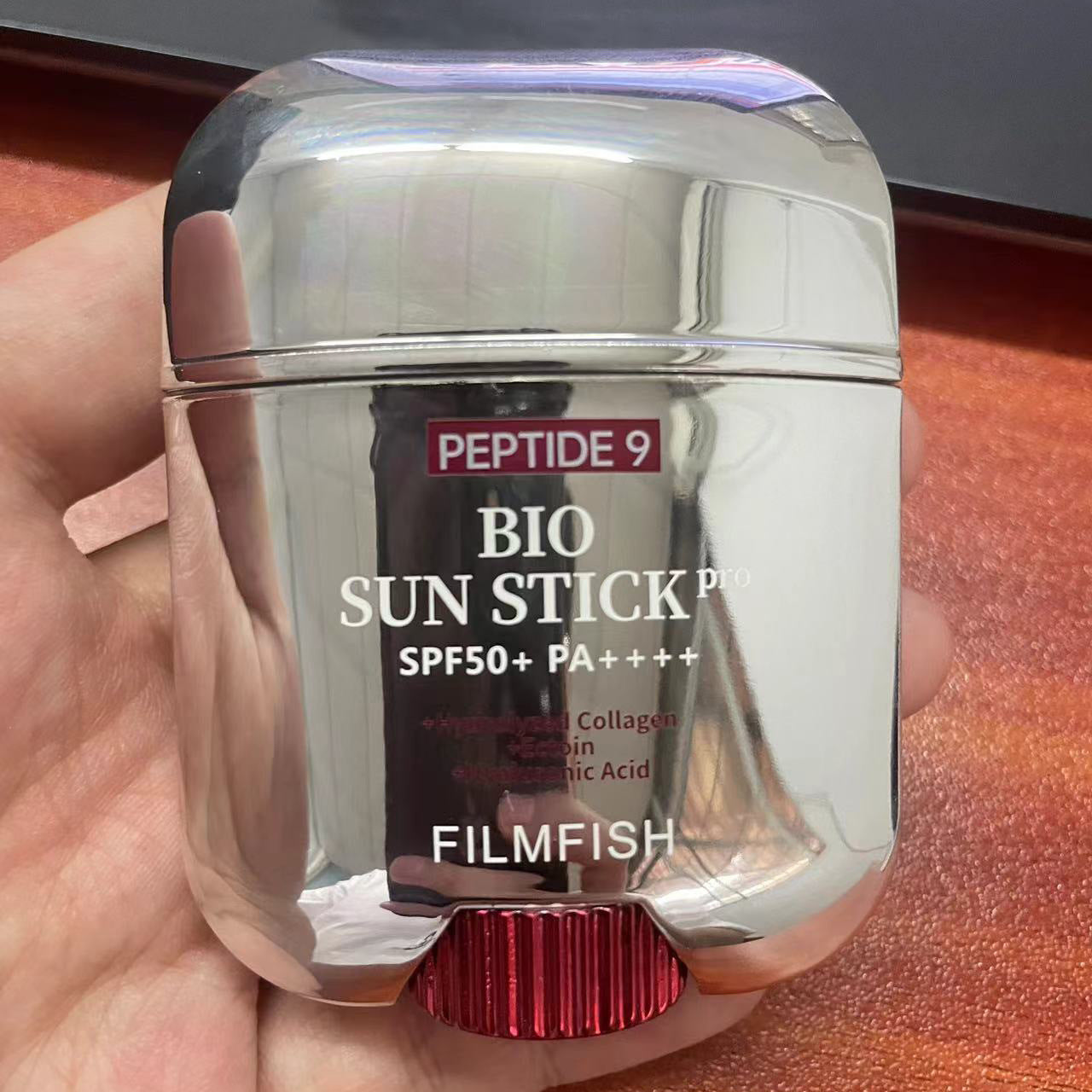 Silver sun stick packaging with visible branding on a hand