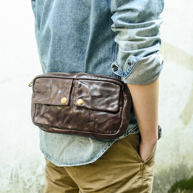 Person wearing a brown leather waist bag with a blurred background