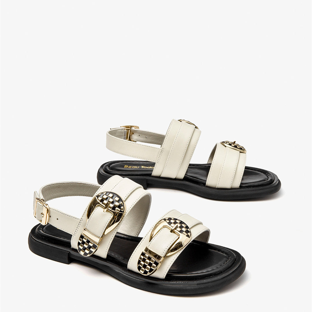 Pair of white sandals with gold buckles on a white background