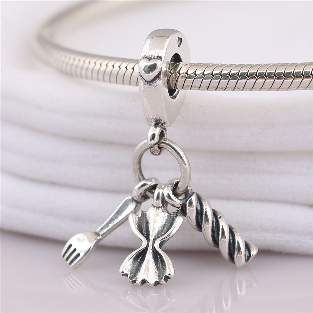 Silver charm with a bow and fork on a white background