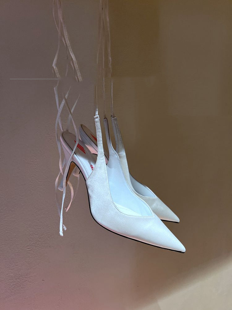 White high-heeled shoes on a reflective surface with a blurred background