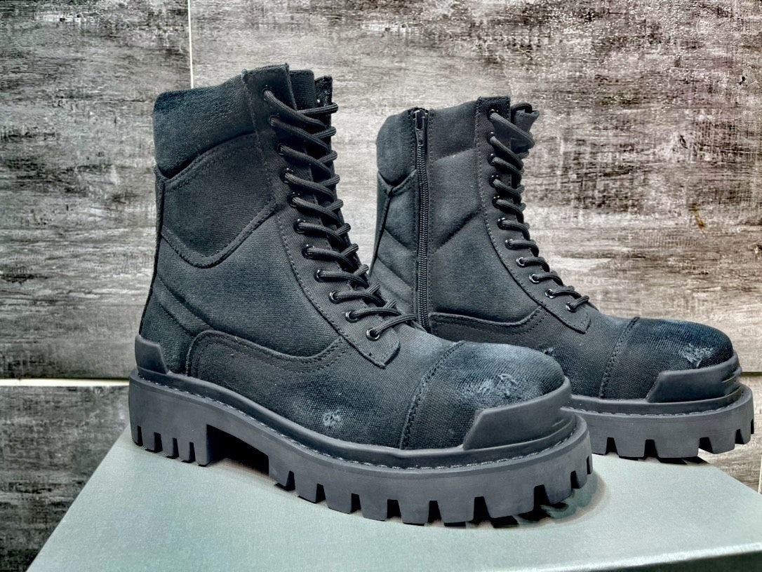 Pair of black leather boots with thick soles on a wooden surface