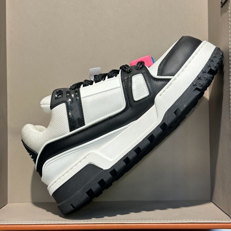 White and black sneaker with a pink sole on a gray surface
