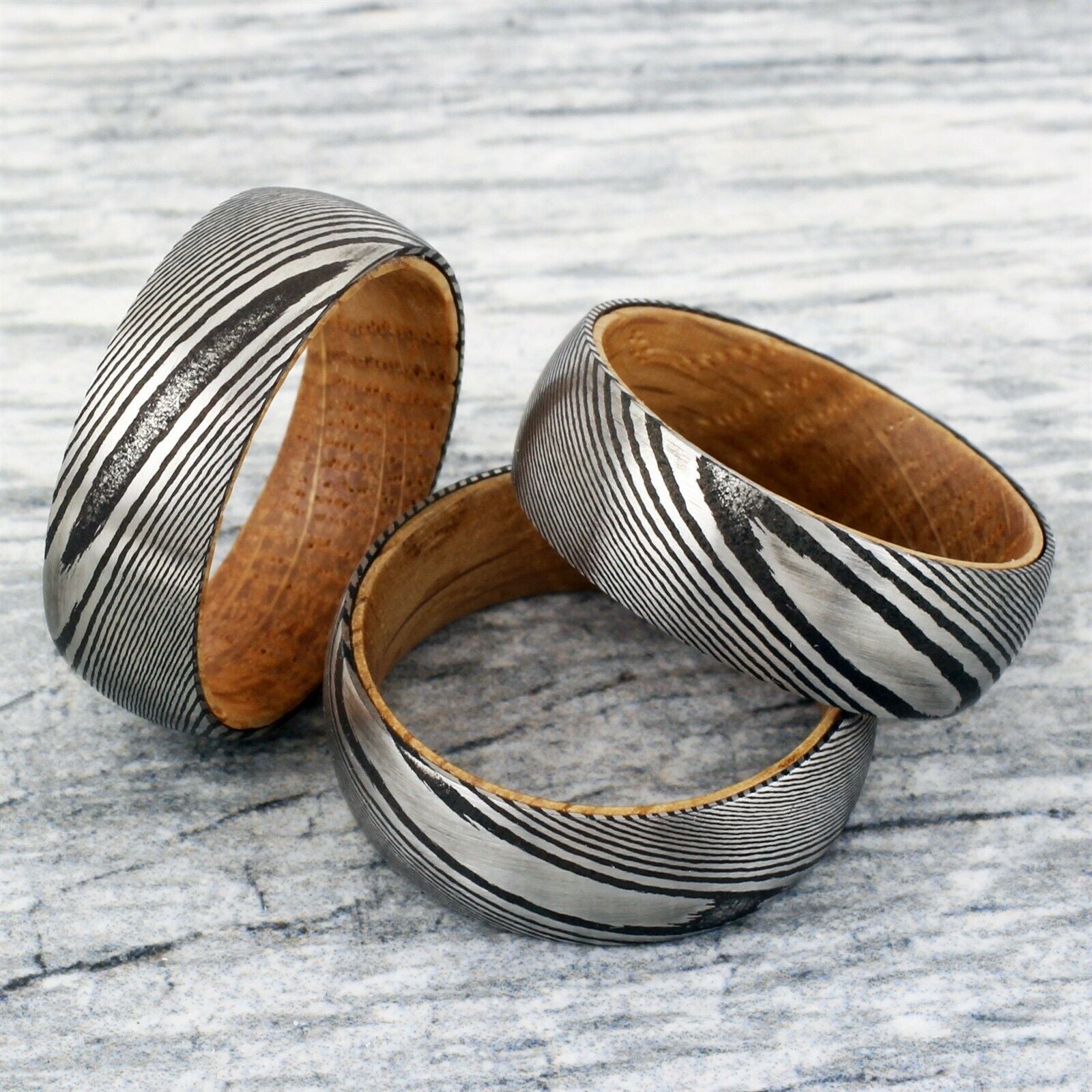 Three metallic and wooden bracelets on a textured surface