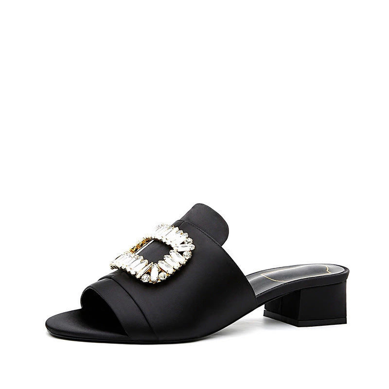 Black sandal with a decorative gemstone buckle on a white background