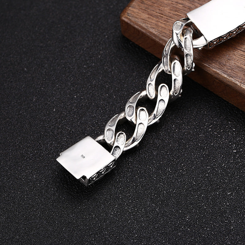 Silver chain bracelet on a dark surface with a wooden block