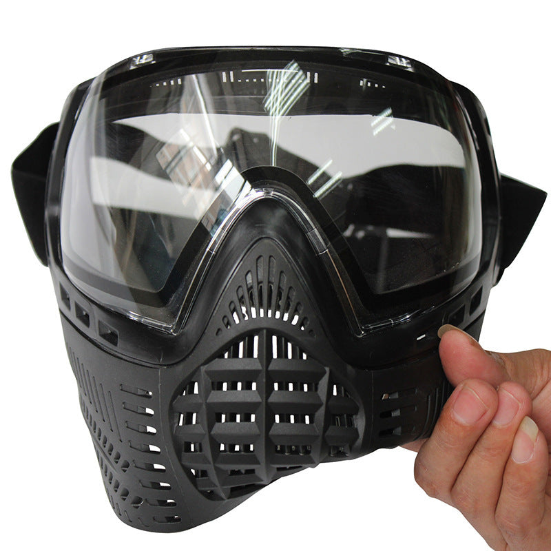 Black tactical mask with clear visor held by a hand on a white background