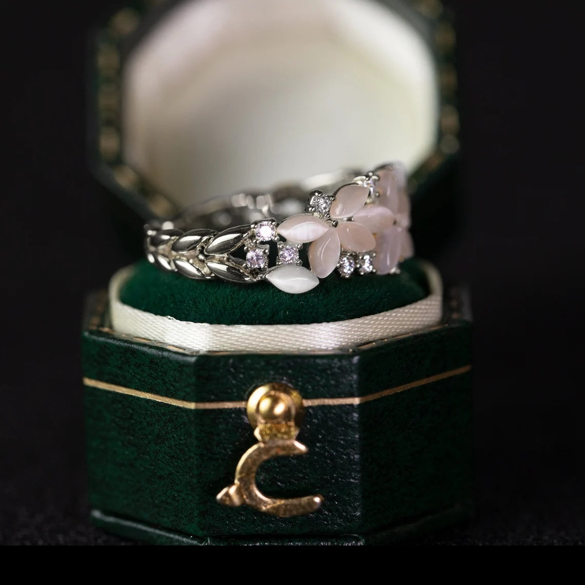 Two rings on a green jewelry box with a black background