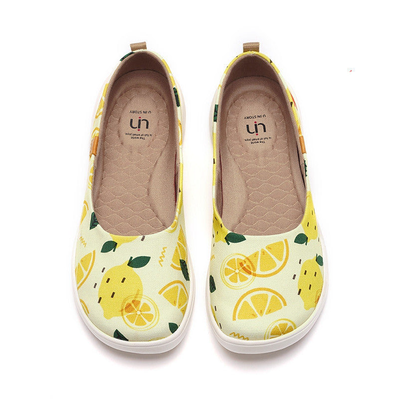 Pair of yellow slip-on shoes with lemon pattern on a white background