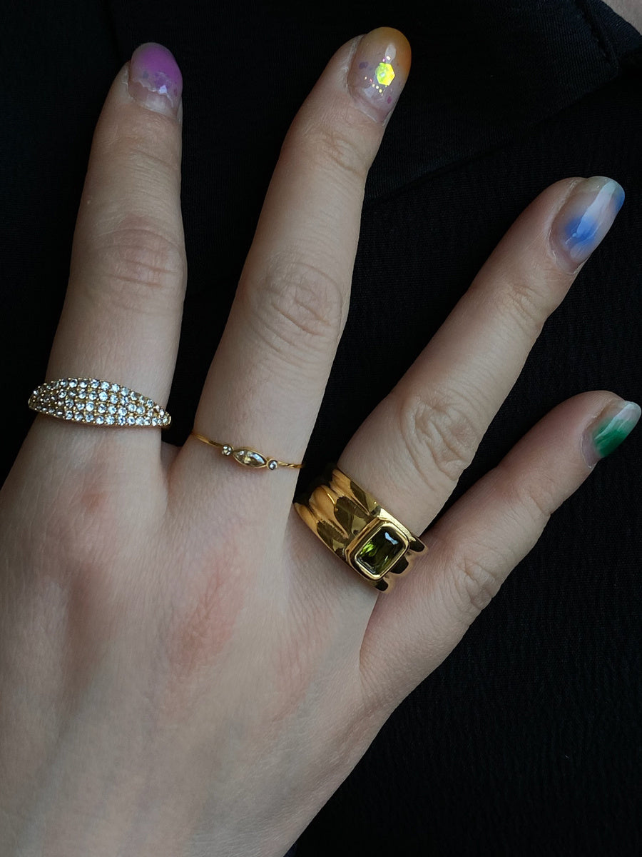 Hand wearing two rings with a dark background