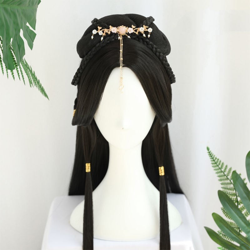 Black wig with decorative headpiece on a mannequin head against a white background with green leaves.