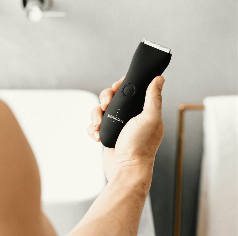 Person holding a black Meridian grooming tool in a bathroom setting